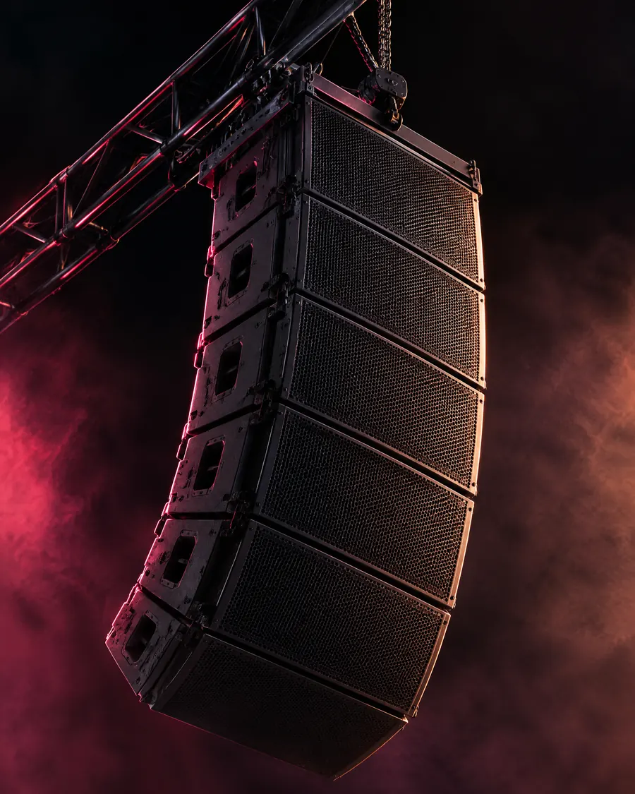 Sistema de altavoces line array colgado de una estructura durante un concierto nocturno